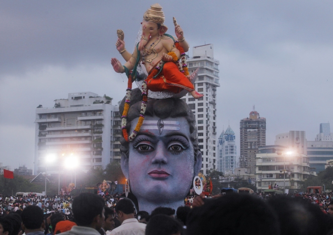 Devotees watch idols of Ganesh, and Lord Shiva as they are placed on the seashore before immersion on the last day of Ganesh Chaturthi, in Mumbai.