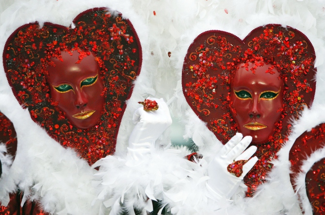 A couple wear masks in the shape of a heart while posing for tourists in Saint Mark's square during the carnival in Venice.
