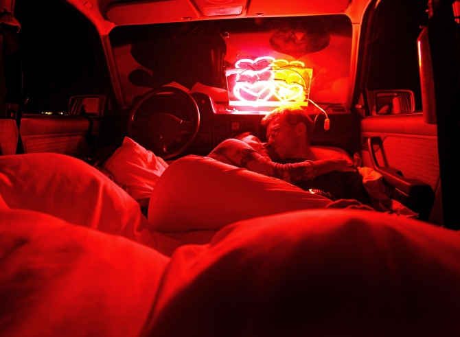 A couple lies inside a car, whose interior has been converted into a hotel bedroom, in Amsterdam.