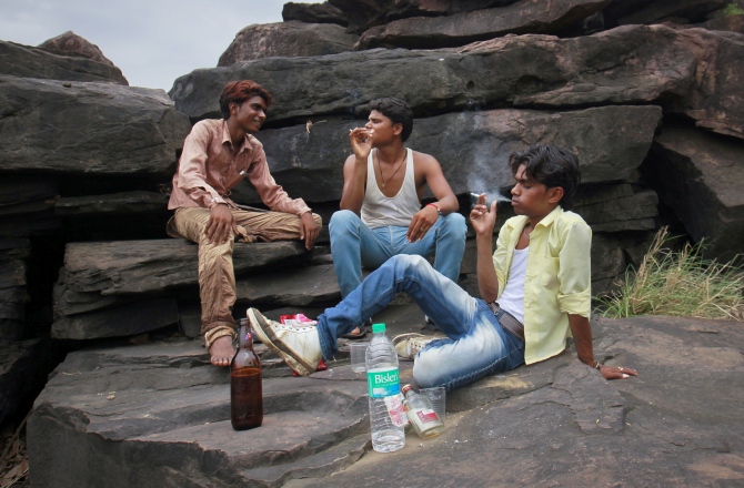 Gopal Kishan (right), 15, smokes a cigarette as he drinks with his friends on the outskirts of their village near Kota, located in Rajasthan. 