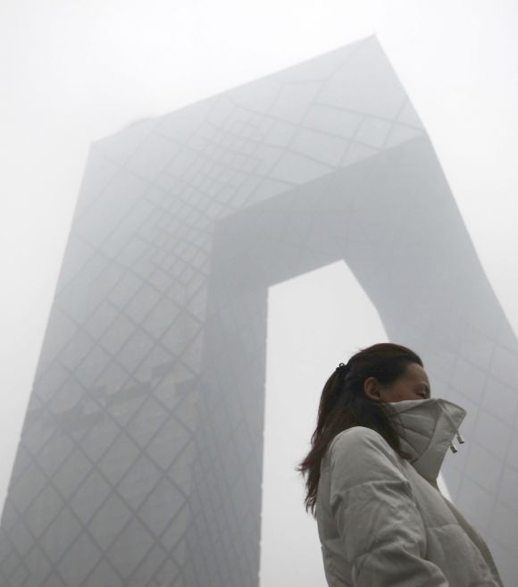 A woman walks past the china Central Television (CCTV) building amid heavy smog in Beijing on Tuesday. China has sent teams of investigators to parts of the country worst hit by air pollution as part of efforts to stop the heavy smog engulfing about 15 percent of the country, including Beijing.