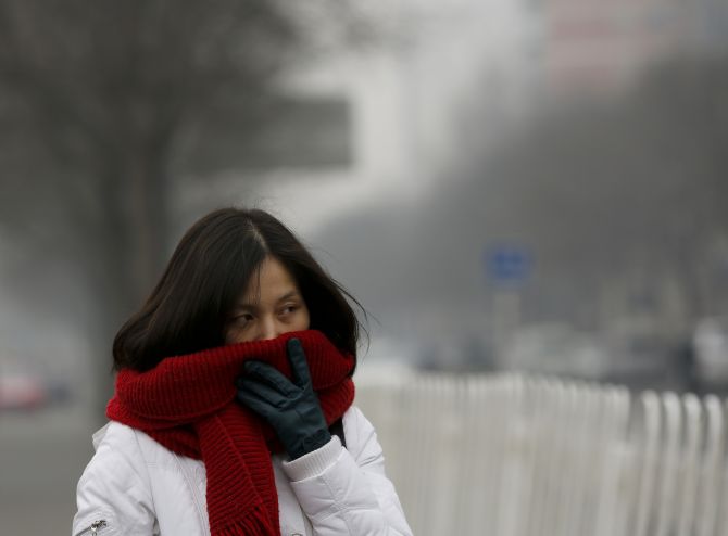 A woman covers her nose and mouth with her scarf amid the heavy haze in Beijing on Monday