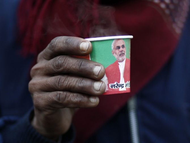 A man holds a paper cup carrying a portrait of Modi during a 'chai pe charcha' initiative in Delhi recently