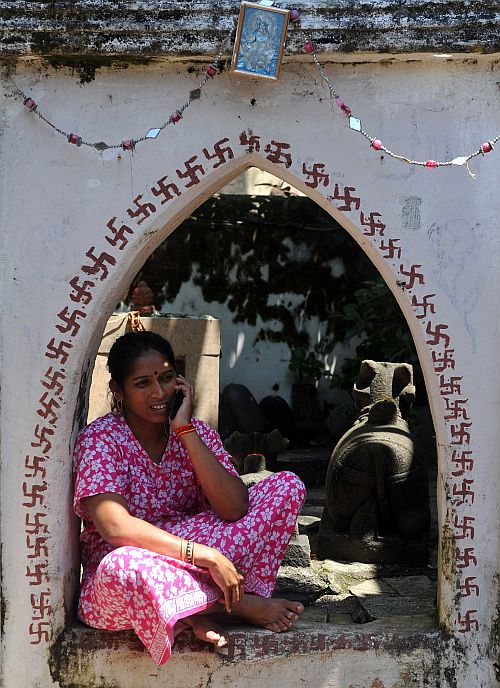 An Indian housewife speaks on her mobile phone as she sits outside her home in Mumbai