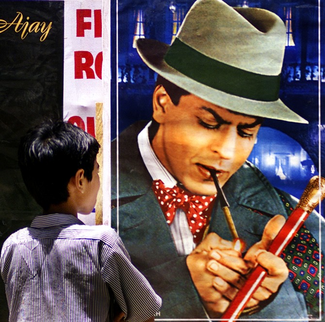 A boy looks at a poster of Bollywood actor Shah Rukh Khan smoking a cigarette during an anti-tobacco demonstration in Mumbai.