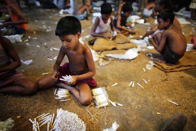 Children fill up empty cigarettes manually with locally grown tobacco in a small bidi factory at Haragach in Rangpur district, Bangladesh.
