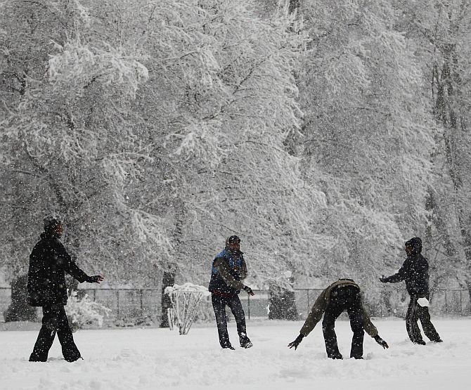 Tourists enjoy a snowball fight during snowfall on a cold winter morning in Srinagar