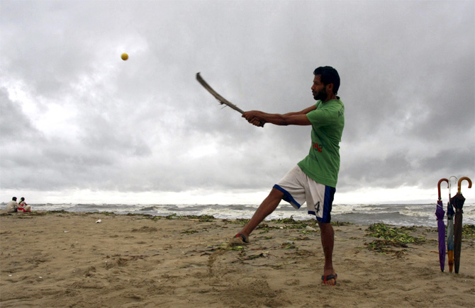 A man plays cricket on a beach in Kerala