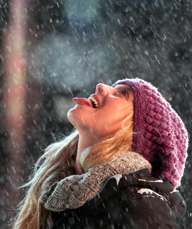 A tourist catches snowflakes on her tongue during snowfall in Times Square, New York