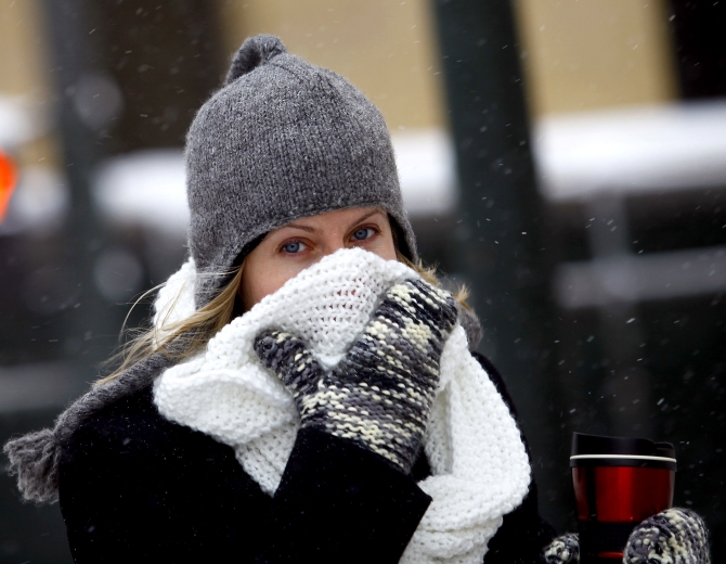 A woman covers her face from the cold as the area deals with record breaking freezing weather