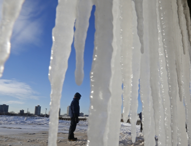 A man is framed by icicles along a beach in Chicago, Illinois 