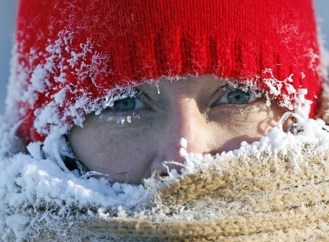 Ice from the breath of Gail Davis forms around her face as she exercises by walking outside in Minneapolis