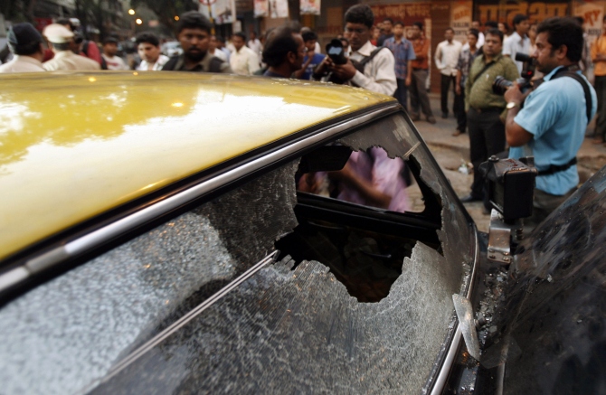 Onlookers and photographers gather near a taxi, ransacked and damaged by the followers of Maharashtra Navnirman Sena, in Mumbai.