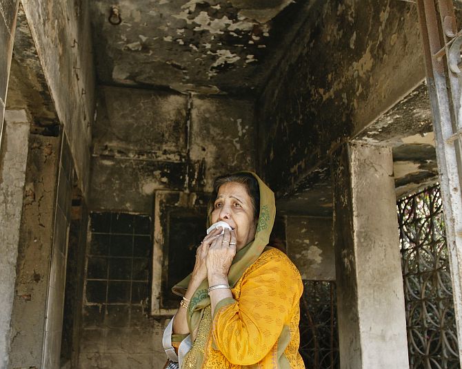 A survivor weeps inside her home that was burnt during the riots.