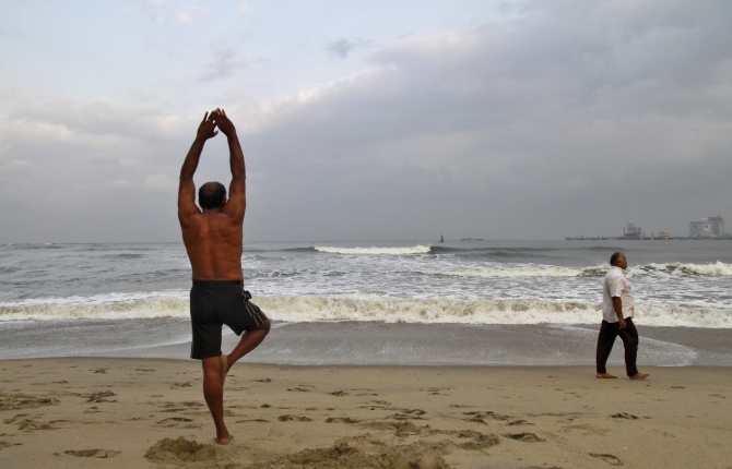 A man exercises on a beach against the backdrop of pre-monsoon clouds in Kochi