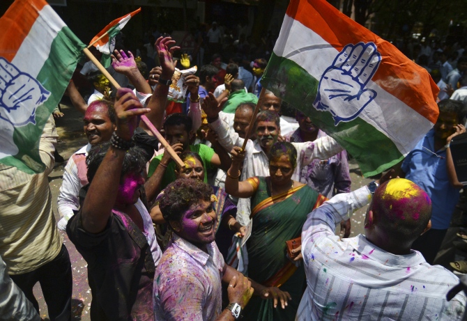 Supporters of India's ruling Congress party celebrate as they hold their party flags outside a vote counting centre in Bangalore