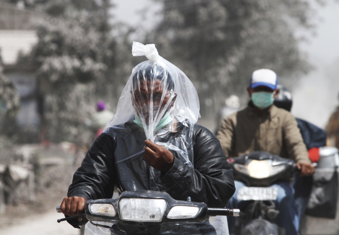 A villager riding a motorcycle covers his face with a plastic sheet to avoid ash from Mount Sinabung volcano at Tiga Pancur village in Karo district, Indonesia's North Sumatra province.