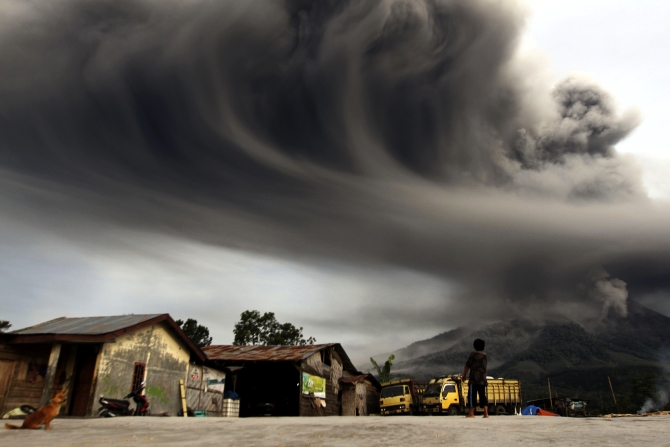 A woman looks on as Mount Sinabung spews ash, as pictured from Sibintun village in Karo district, Indonesia's north Sumatra province.