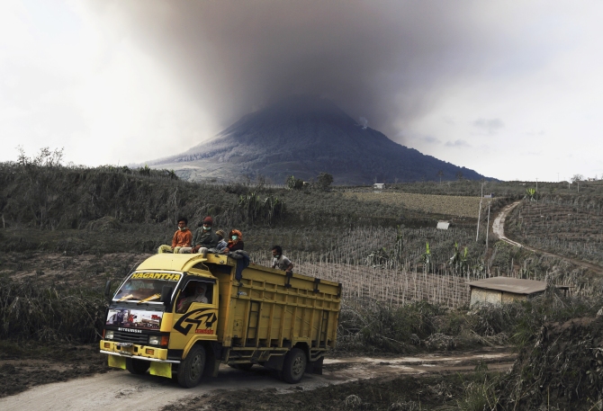 Villagers travel on a truck to inspect the damage done to their homes during earlier Mount Sinabung eruptions, and to collect their belongings, at Kuta Gugung village in Karo district, Indonesia's North Sumatra province.