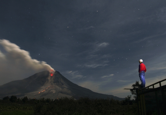 A man looks at Mount Sinabung spewing ash from Jraya village in Karo district, Indonesia's North Sumatra province.