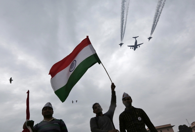 A supporter of the Aam Aadmi holds up India's national flag during a protest, as Indian Air Force aircrafts fly past as part of Republic Day rehearsals, in New Delhi