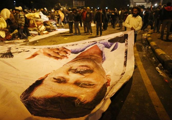 A supporter of Aam Aadmi Party removes a poster with a portrait of Delhi Chief Minister Arvind Kejriwal from the site of a protest after Kejriwal called off the sit-in protest against the police in New Delhi