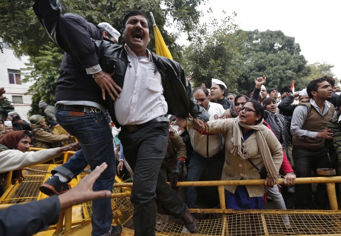 A supporter of the Aam Aadmi Party shouts slogans as he climbs over a police barricade during a protest led by Delhi Chief Minister Arvind Kejriwal in New Delhi