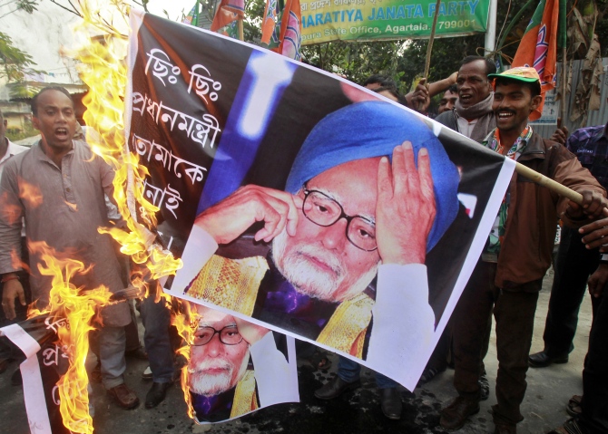 Activists from the Bharatiya Janata Party shout slogans as they burn banners with images of India's Prime Minister Manmohan Singh during a protest in Agartala