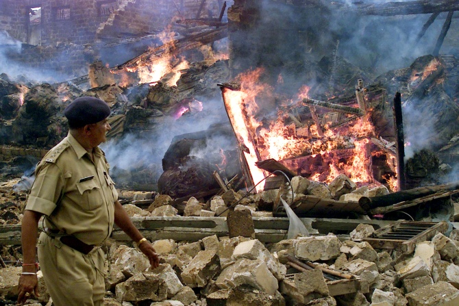 A police officer walks past flames at a building burnt by an angry mob in Veraval, 320 km southwest of Ahmedabad, Gujarat in this photograph taken on July 28, 2004.