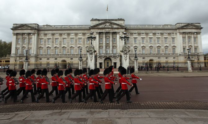 Royal guards march past the Buckingham Palace in London