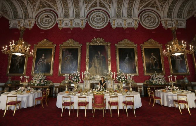 A curator poses while rearranging the coronation banquet exhibit during a media preview of the exhibition The Queen's Coronation 1953 at Buckingham Palace 