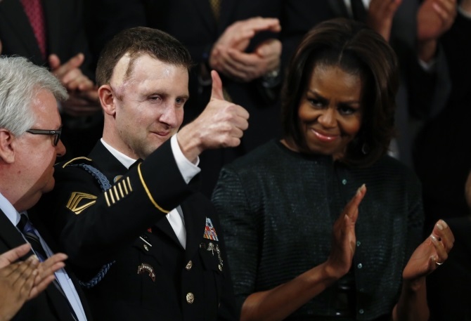 US first lady Michelle Obama applauds US Army Ranger Sgt. First Class Cory Remsburg, injured while serving in Afghanistan