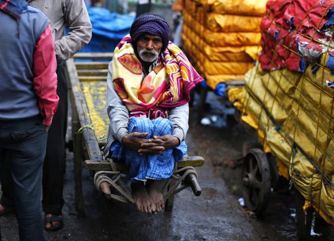 A labourer sits on a cart during a cold morning in Delhi