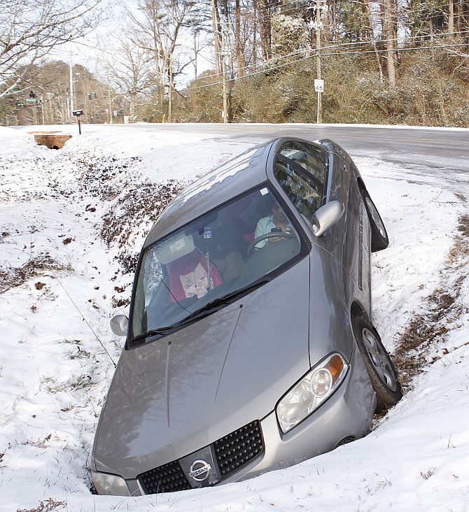 A driver uses a mobile phone in a car after running off the roadway due to a snow storm in Atlanta, Georgia