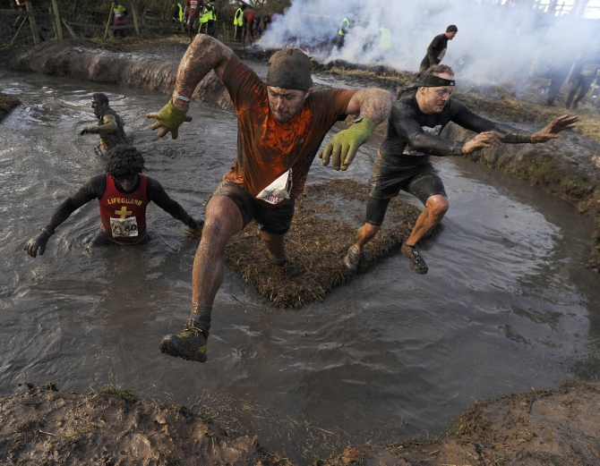 Competitors jump across water during the Tough Guy event.