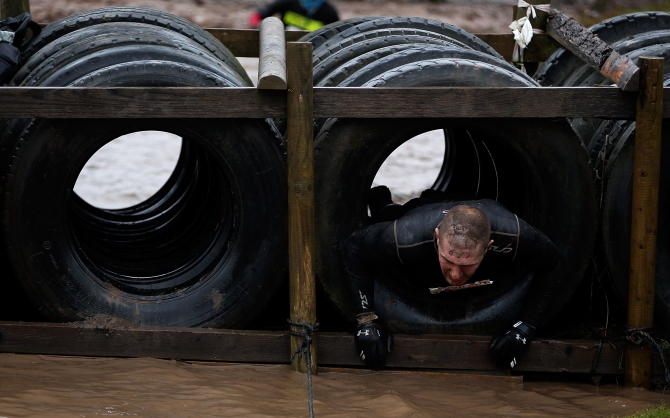 A participant pulls himself through some tyres during the Tough Guy Challenge in Telford, England