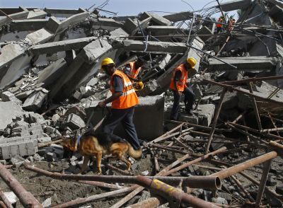 Rescuers try to locate survivors in the rubble of a collapsed building in Chennai, July 2014.