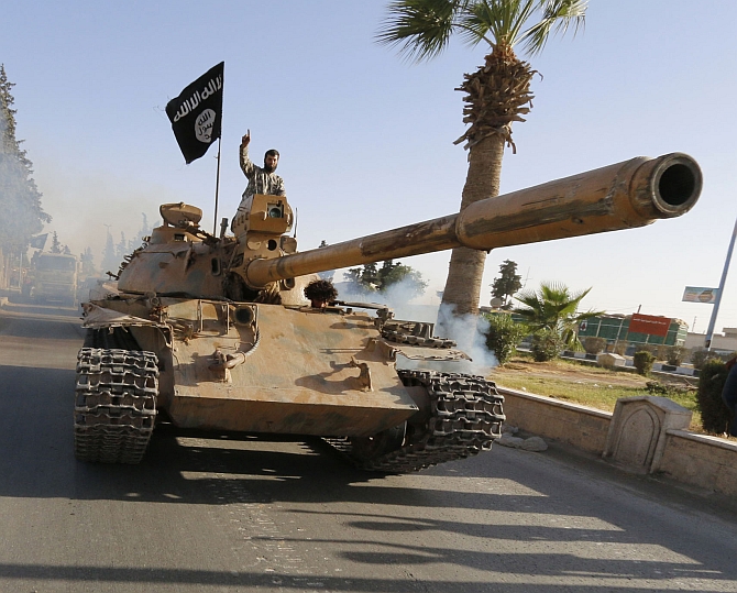 Militant Islamist fighters on a tank take part in a military parade along the streets of northern Raqqa province of Iraq
