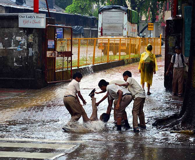 Children play in a puddle of water outside their school in Dadar, Mumbai 