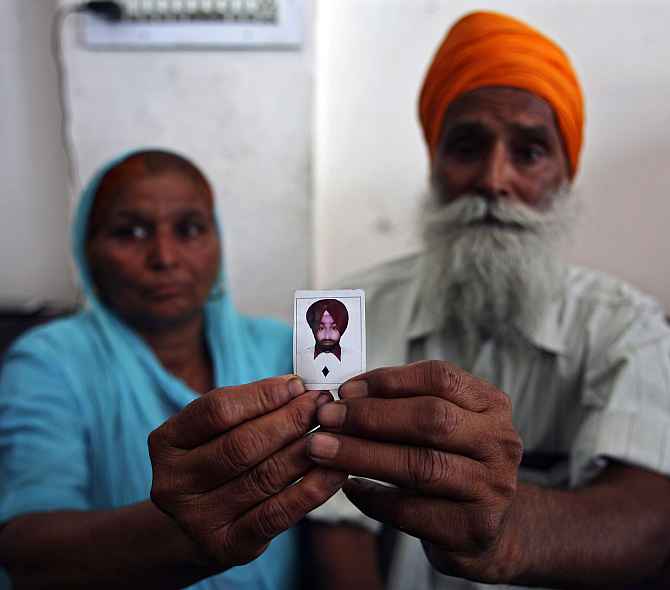 The parents of a construction worker stranded in Iraq show their son's photo, in Amritsar.