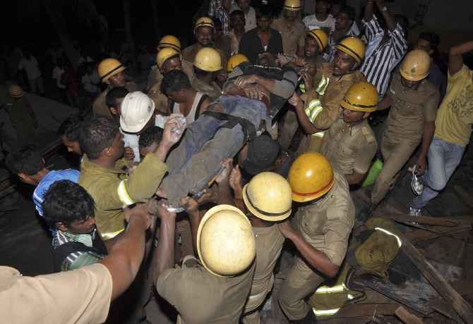 Rescue workers pull out an injured man from the rubble of an under-construction building that collapsed in Porur near Chennai