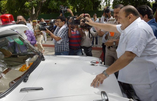 Mukesh Sharma stands in front of the car of Railway Minister DV Sadananda Gowda during the protest