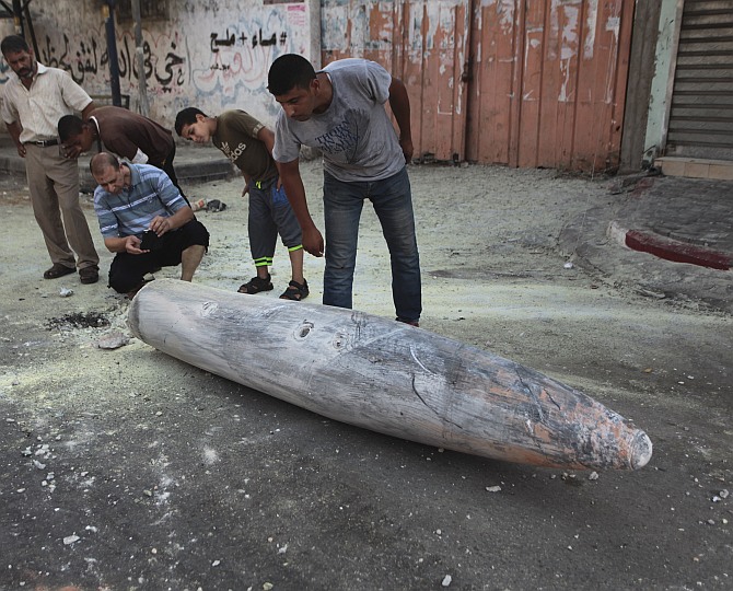 Palestinians look at the remains of a missile which witnesses said was fired by an Israeli aircraft on a street in Deir El-Balah in the central Gaza Strip July 11