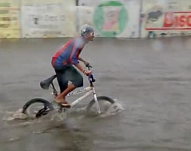 A man cycle through a flooded road in Mumbai 