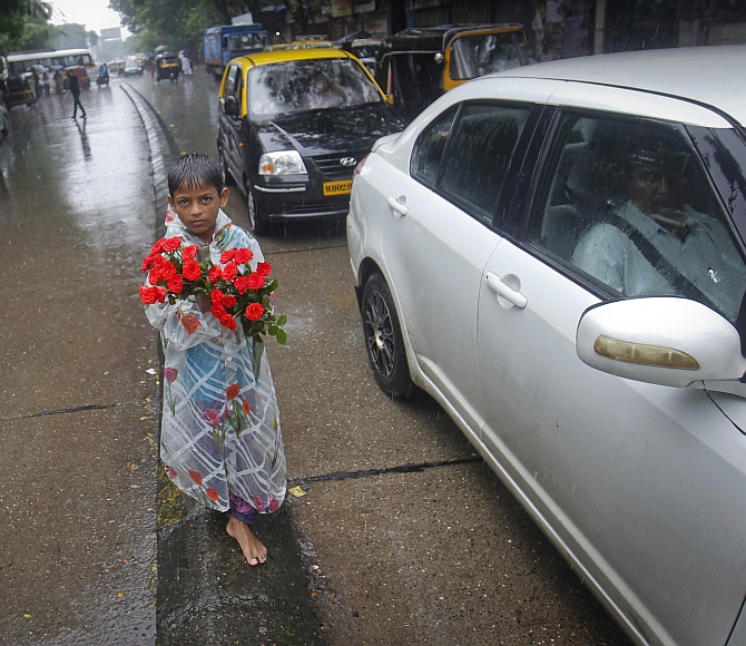 A boy sells roses while standing on a road divider during monsoon rains in Mumbai 