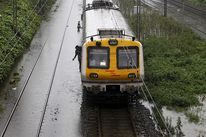 A suburban train passes over waterlogged railway tracks during heavy monsoon rains in Mumbai 