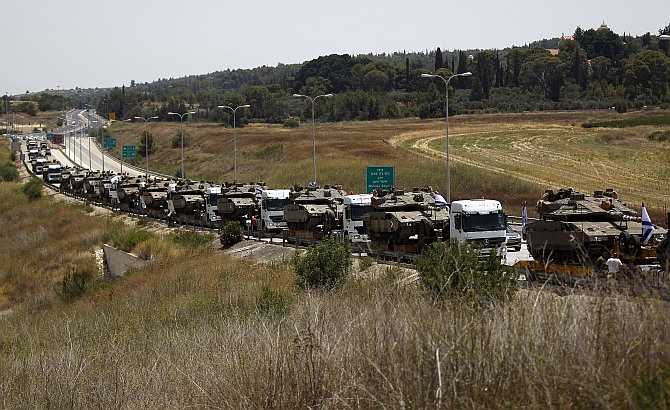 A convoy of Israeli lorries carrying army tanks can be seen on a road leading to southern Israel, at Latrun, near Jerusalem July 12