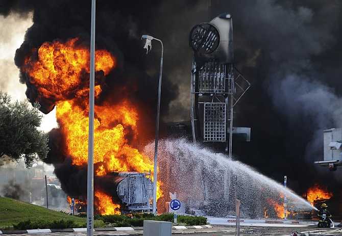  Israeli firefighters extinguish a fire that broke out after a rocket hit a petrol station in the southern Israeli city of Ashdod