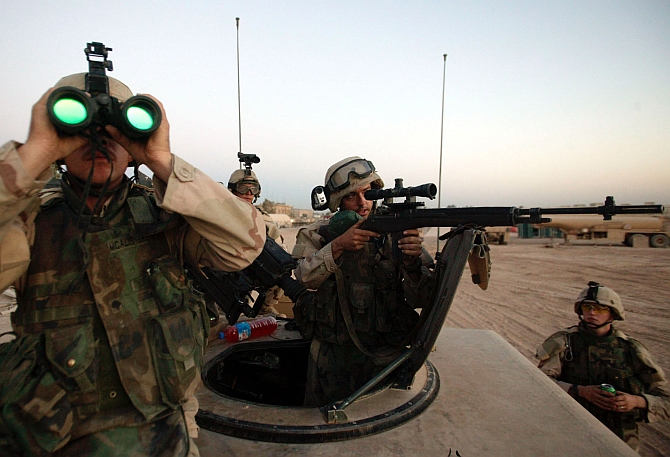 US army sniper takes aim at a suspected enemy observer looking in at Camp Eagle from a neighborhood outside of Sadr City, Baghdad