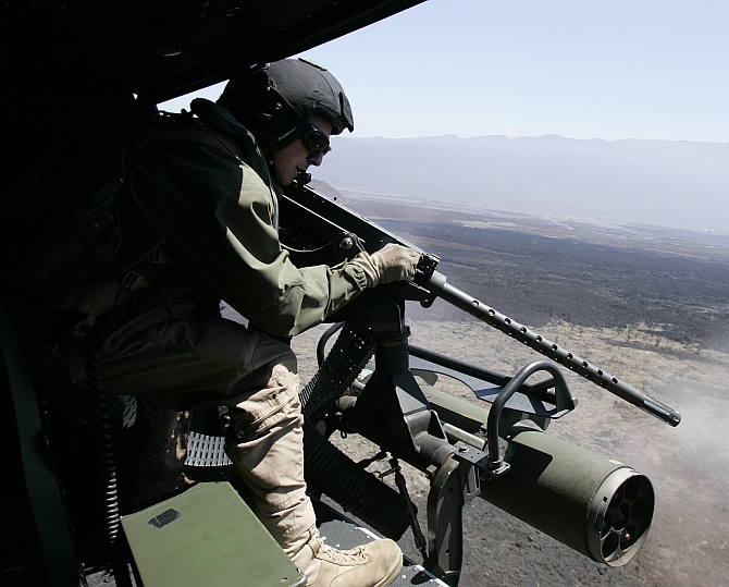 A US marine fires a machine gun at targets, from a Huey attack helicopter during live fire training for the multi-national military exercise RIMPAC at Pohakuloa Training Area on the island of Hawaii